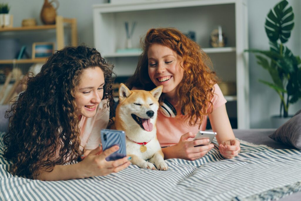 two women laying on a bed with a dog