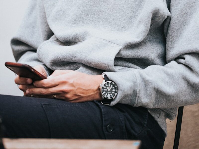 man in gray hoodie using smartphone