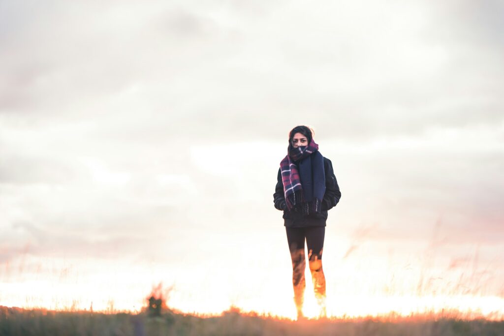 woman walking on green grass under cloudy sky at daytime