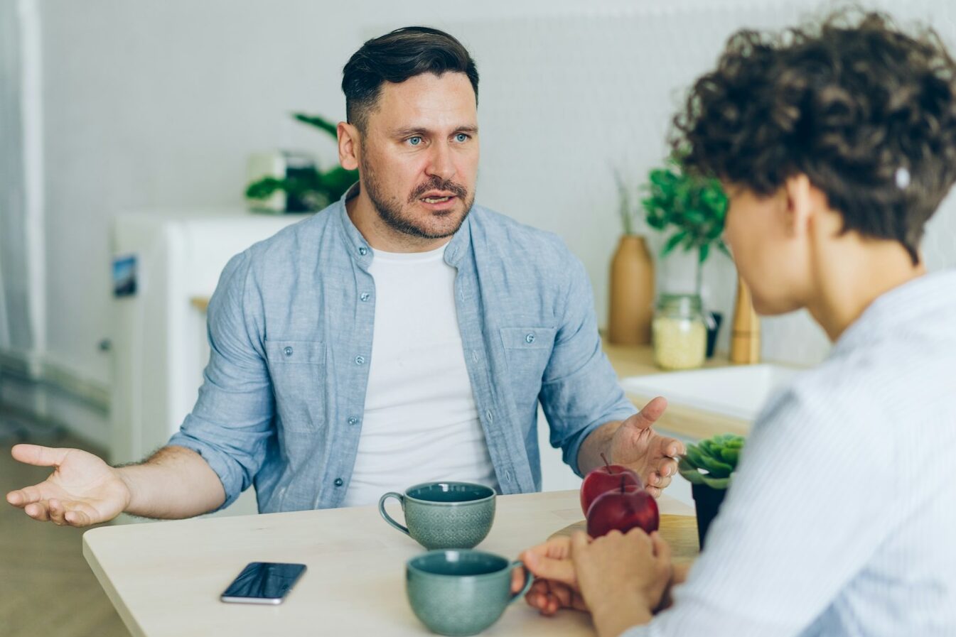 a man sitting at a table talking to a woman