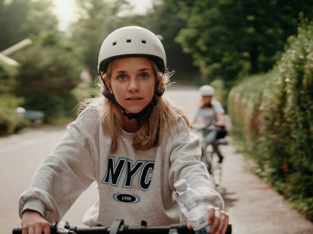 woman in white long sleeve shirt riding bicycle on road during daytime