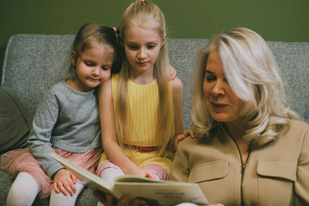 A loving grandmother reading with her two young granddaughters at home, sharing a special bonding moment.