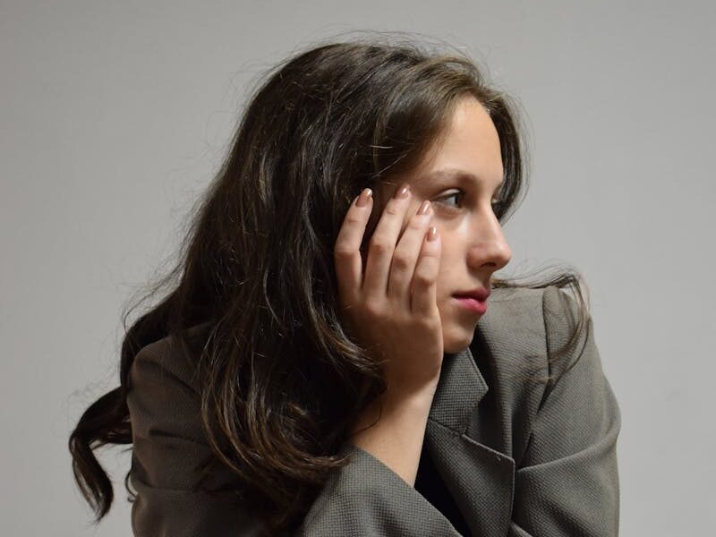 Portrait of a woman in a gray blazer, deep in thought.