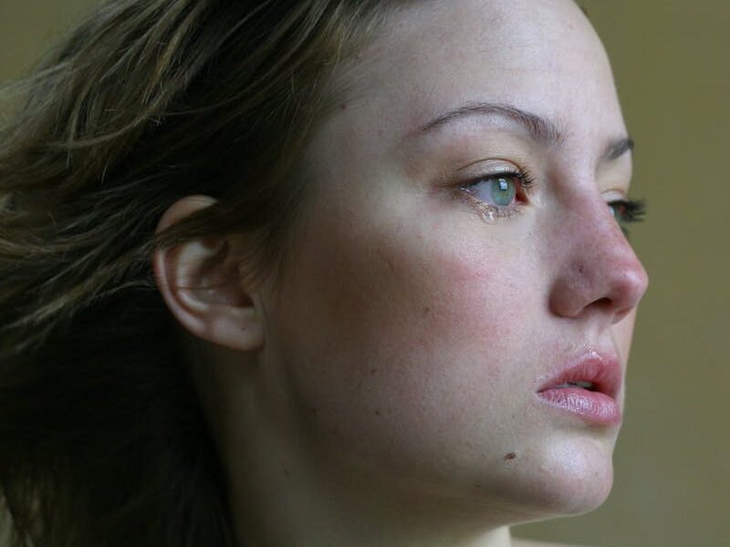 A young woman looks thoughtfully into the distance, capturing emotions with a side profile view.