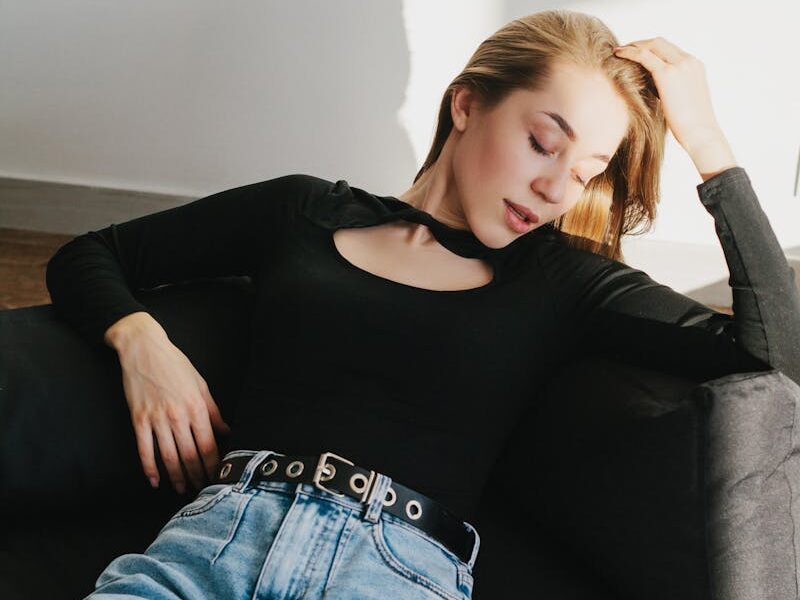 Young woman in casual outfit lounging on a sofa, enjoying a moment of relaxation.