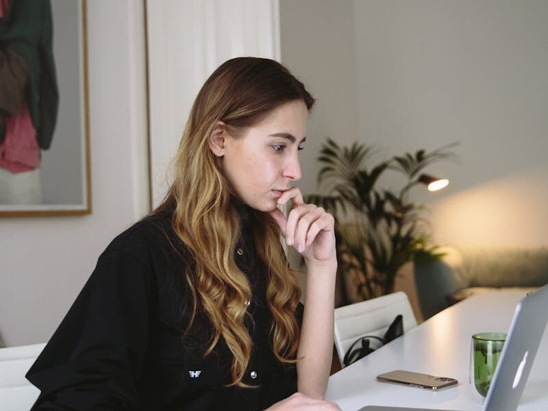 Woman deeply focused on working at a laptop in a stylish home office setting.