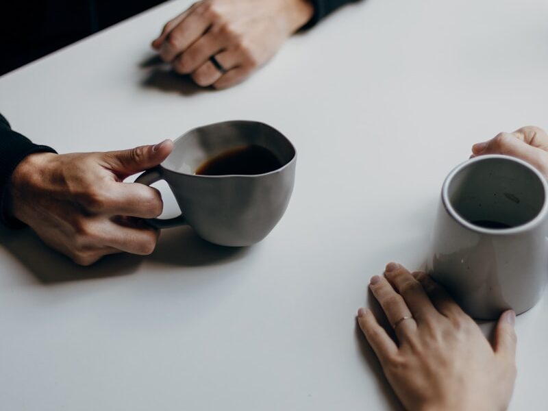 a couple of people sitting at a table with cups of coffee