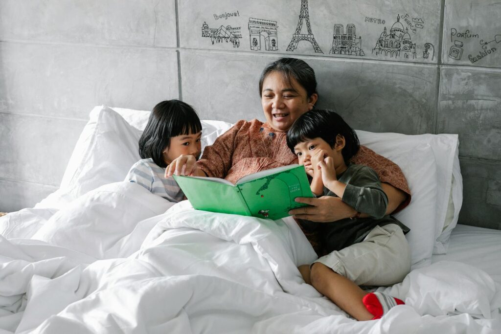 A grandmother reads a storybook to her two grandchildren in a cozy bedroom setting, fostering family bonds.