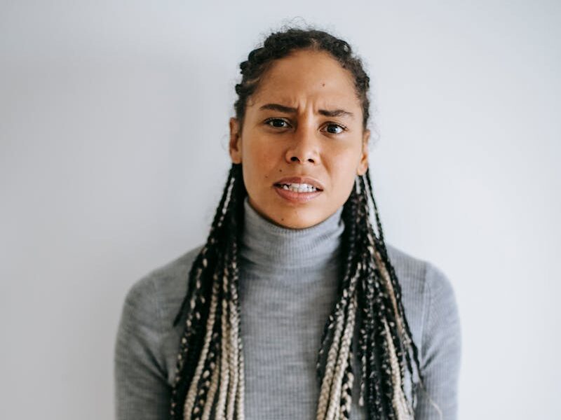 An adult black woman showing frustration and displeasure indoors with a gesture.