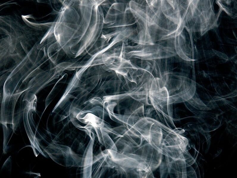 Intricate patterns of swirling smoke on a black background, creating an abstract visual.