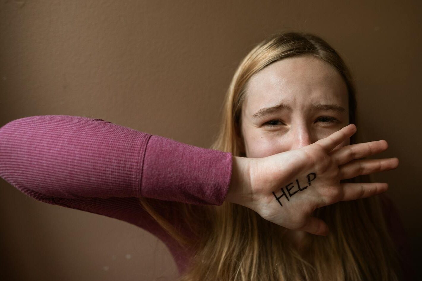 A woman with 'HELP' written on her palm. Emotion and assistance theme.