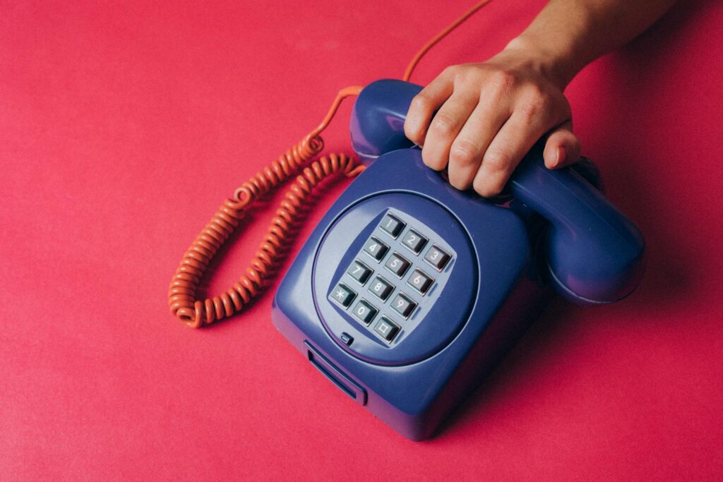 Close-up of a hand holding a vintage blue telephone, evoking nostalgia and retro vibes.