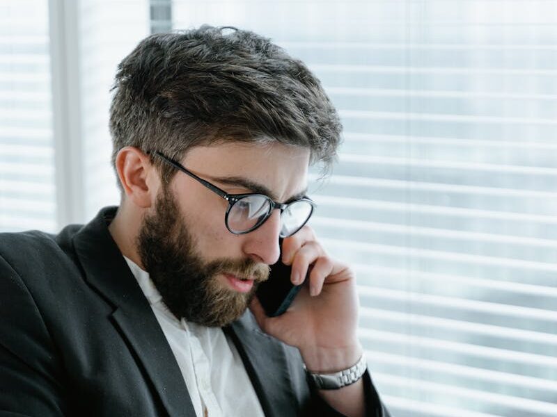 Focused businessman in office, analyzing documents while on a phone call.