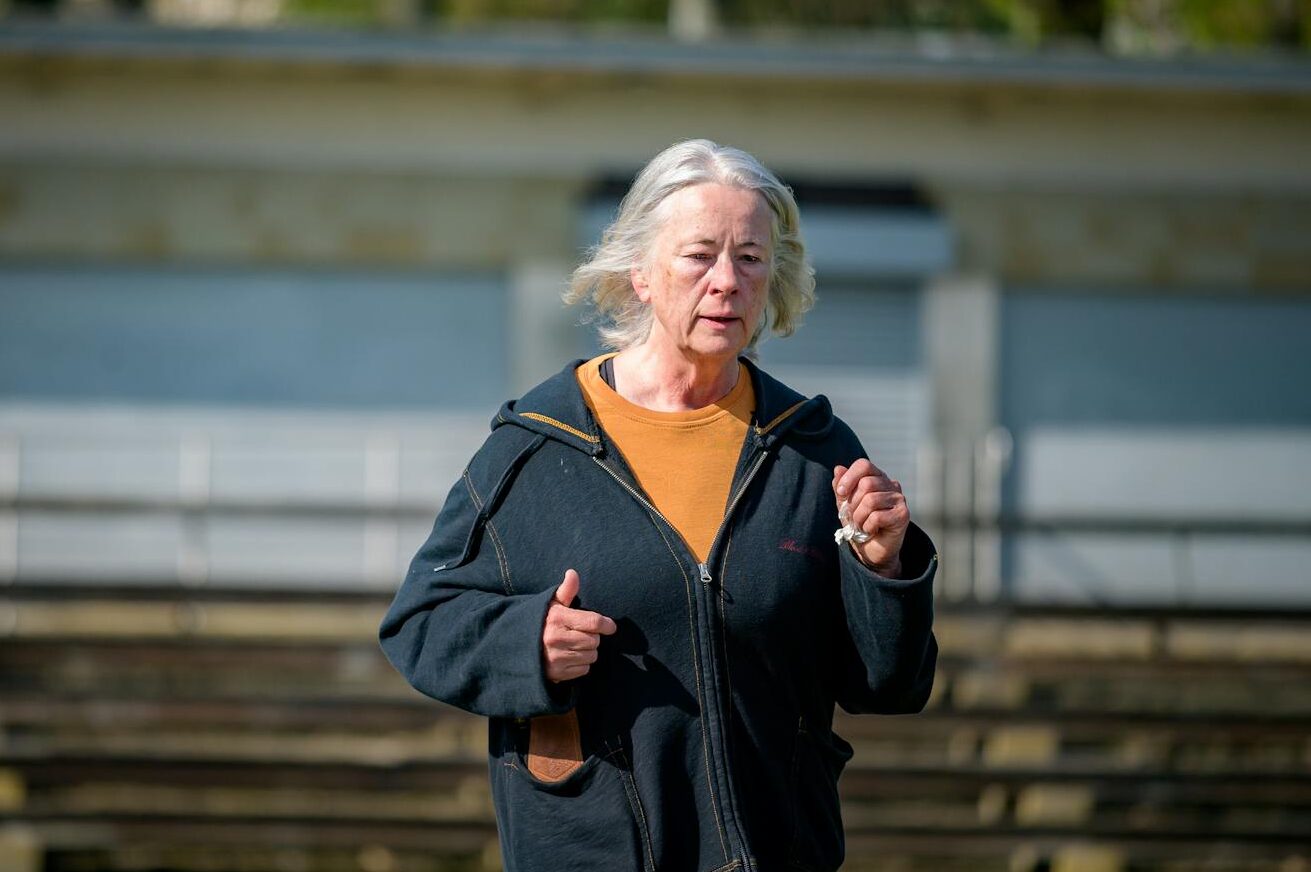 Elderly woman jogging on a bright day, showcasing active lifestyle and wellness in the urban outdoors.