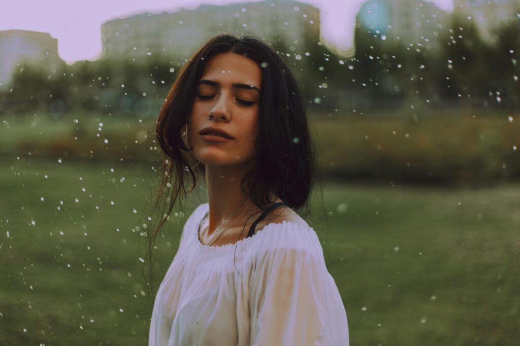 Serene portrait of a young woman enjoying the outdoors, with gentle rain falling.