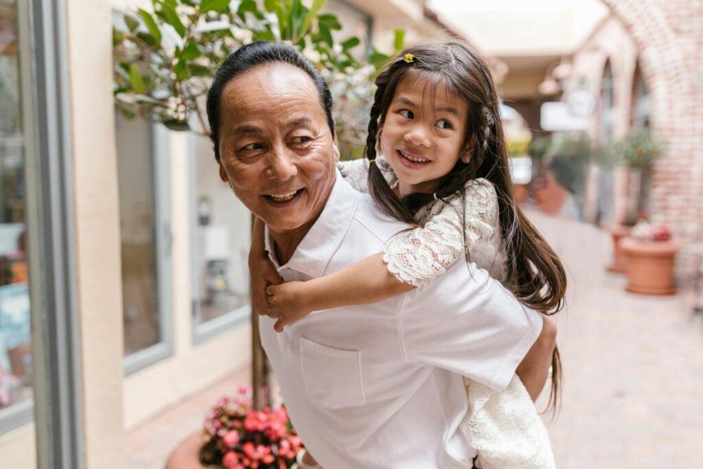 A cheerful moment between an older man and a child enjoying a piggyback ride in a cozy arcade setting.