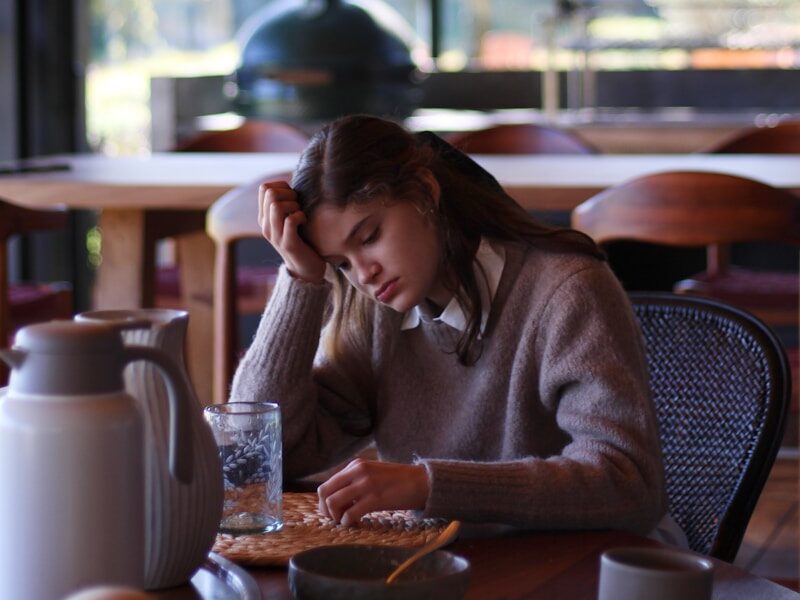 woman in gray long sleeve shirt sitting on brown wooden chair