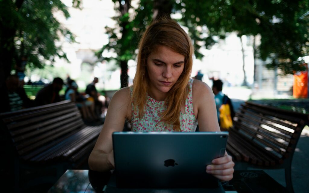 woman sitting on chair while using silver iPad