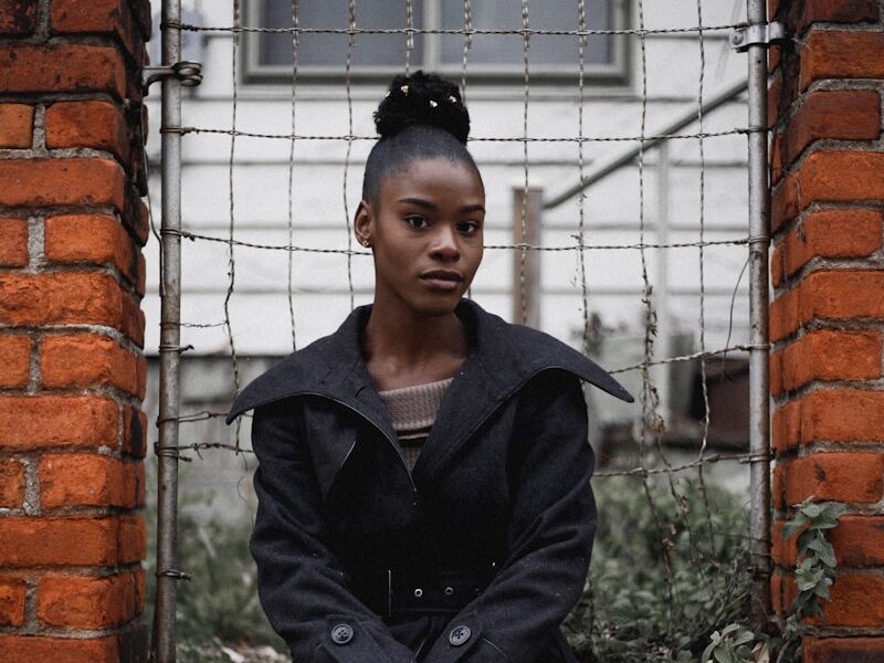 woman sitting near grey gate