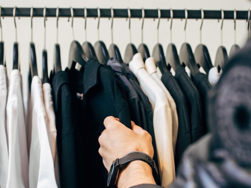 person holding hanged black shirts