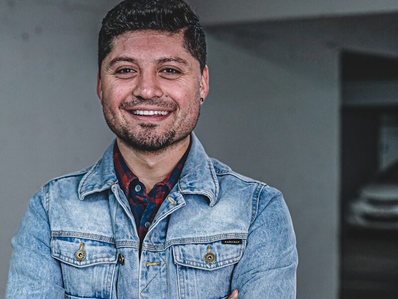 man wearing blue denim jacket smiling
