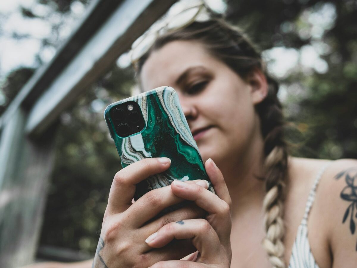 woman in white and blue stripe shirt holding iphone