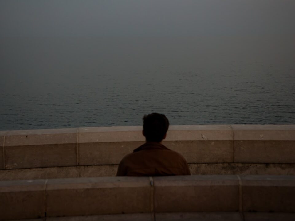 a person sitting on a bench looking at the ocean