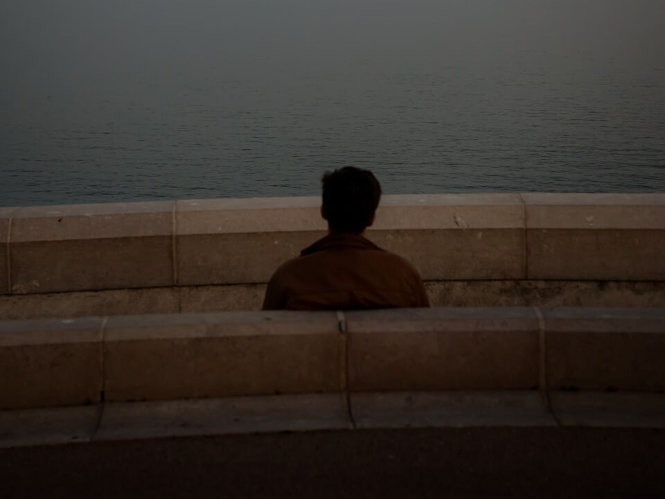 a person sitting on a bench looking at the ocean