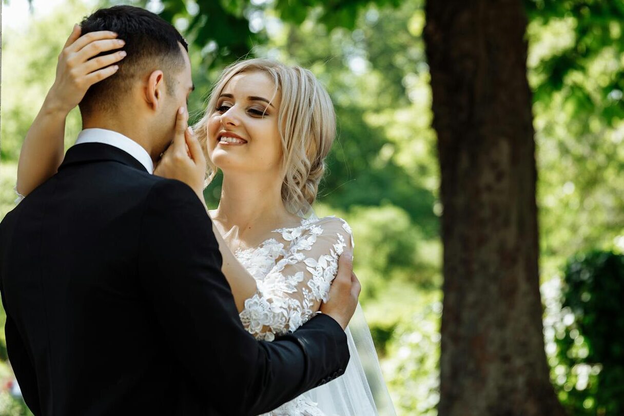 Bride and groom sharing a tender moment under a tree in a Parisian garden.
