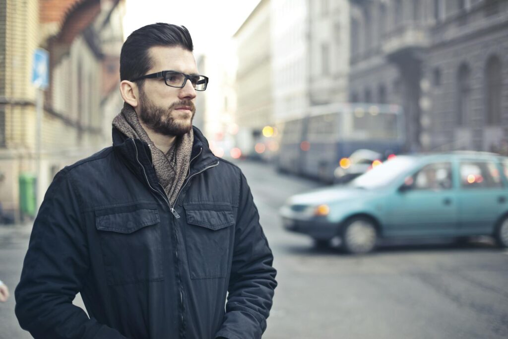 Fashionable man with glasses standing on a bustling street in Budapest, Hungary.