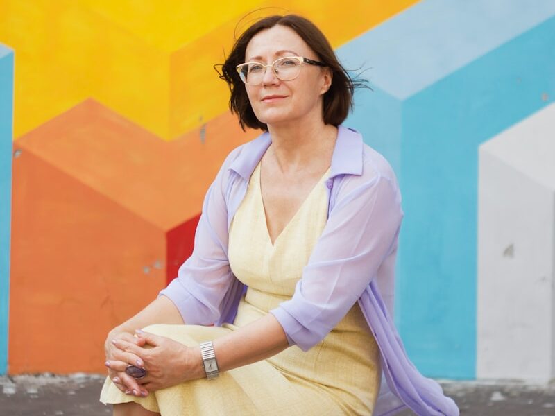 woman in white long sleeve shirt and pink cardigan sitting on concrete floor