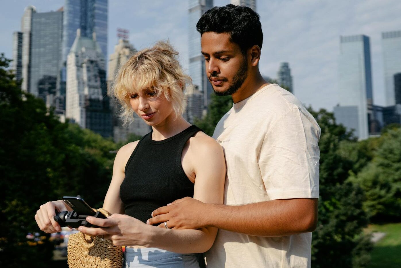 A couple standing together in a city park with skyscrapers in the background, capturing memories.