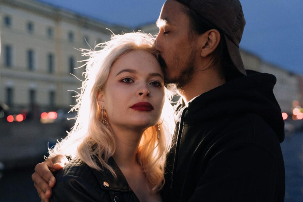 A couple embraces tenderly by the river during a romantic evening in the city.