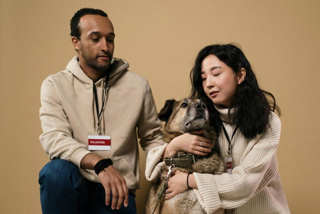 A caring couple of volunteers with a rescue dog in a studio setting.