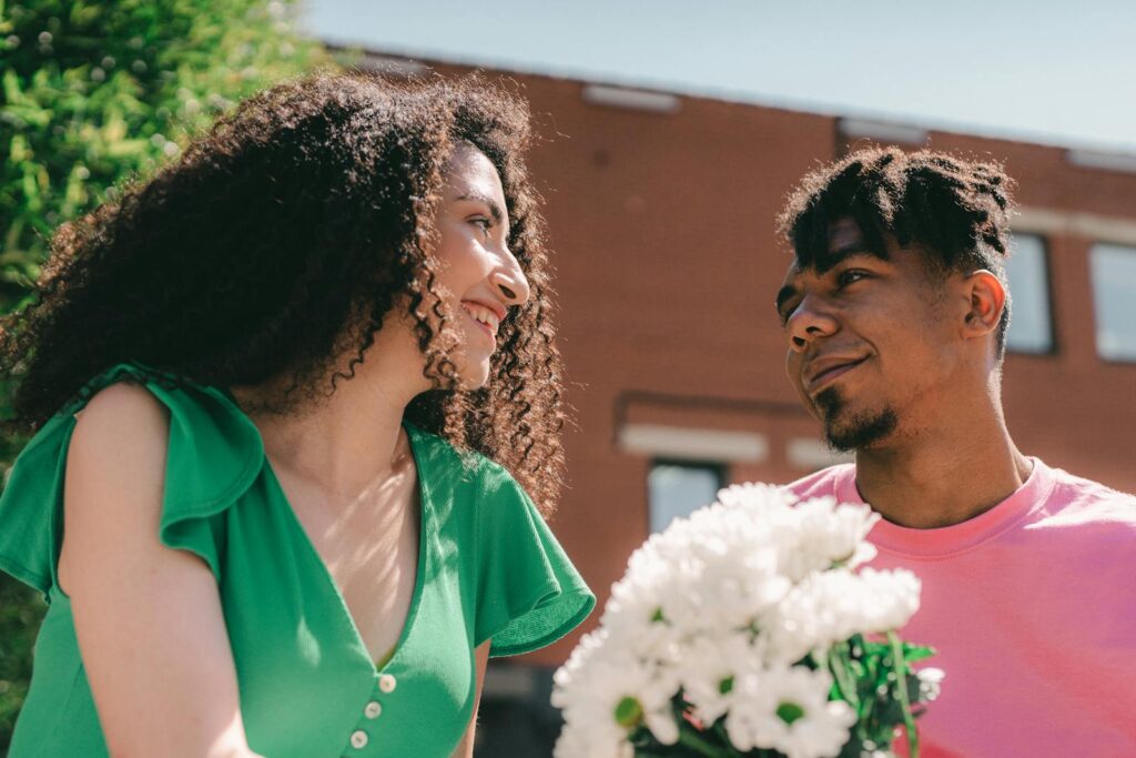 Happy couple in love sharing a tender moment with a bouquet of flowers outdoors.
