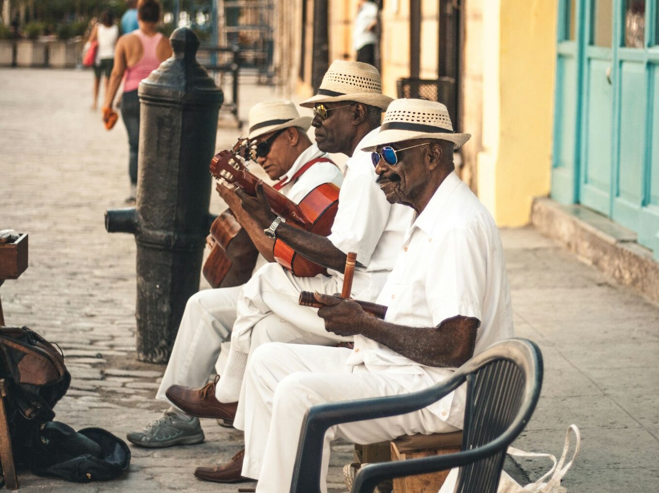 man playing acoustic guitar while sitting on bench